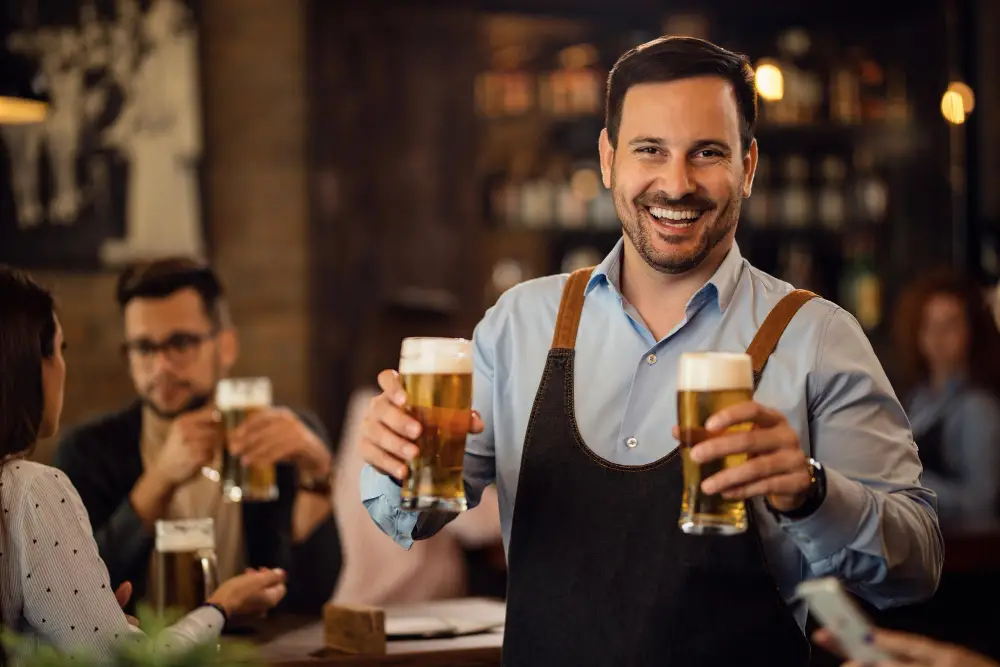 Happy pub owner holding beer glasses - commercial insurance protection for restaurant and bar businesses