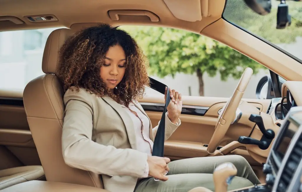 Professional businesswoman demonstrating safe driving practices by wearing a seatbelt in vehicle