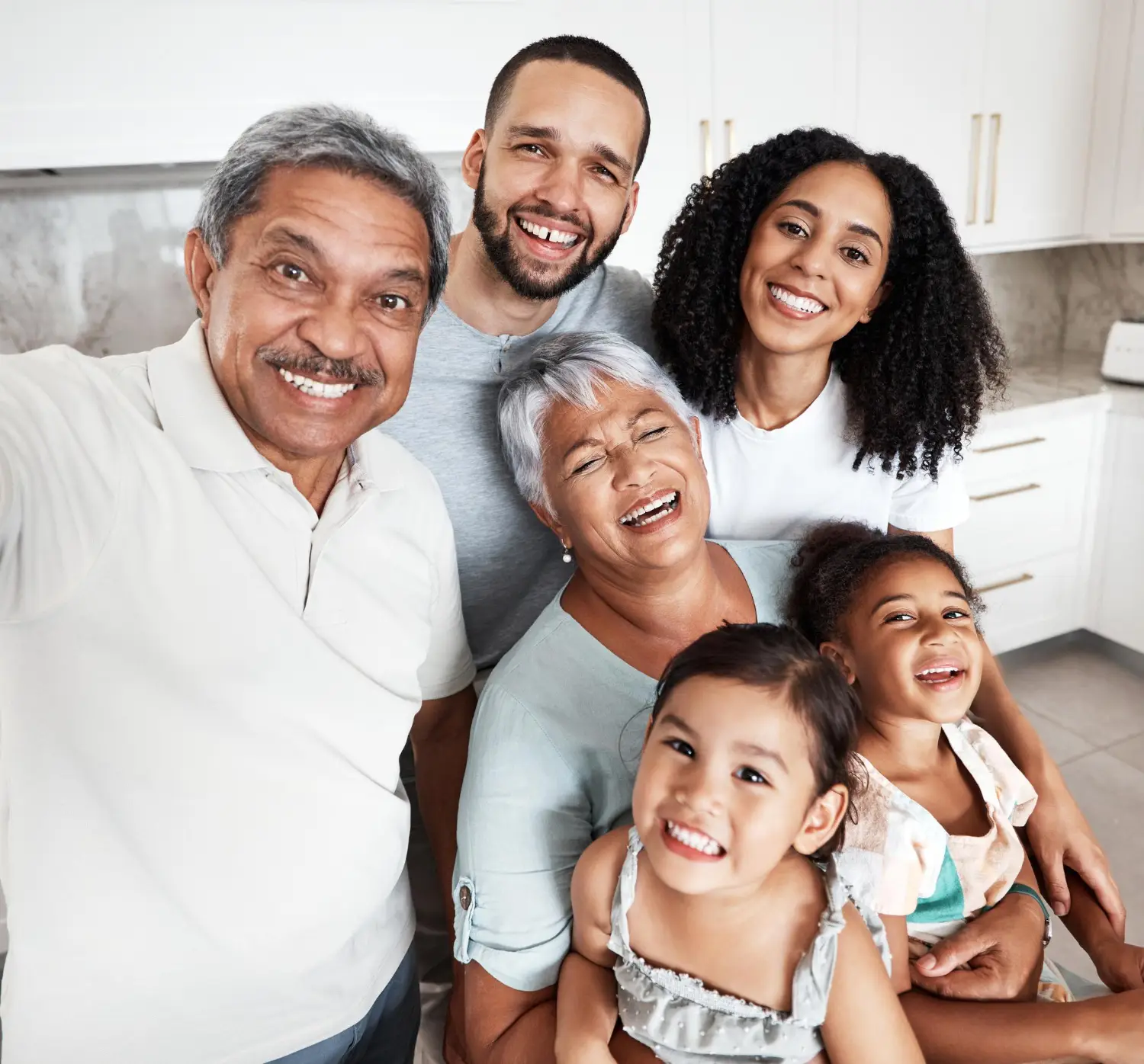 Happy family with young parents and daughters dancing in kitchen, enjoying peace of mind through comprehensive life insurance.