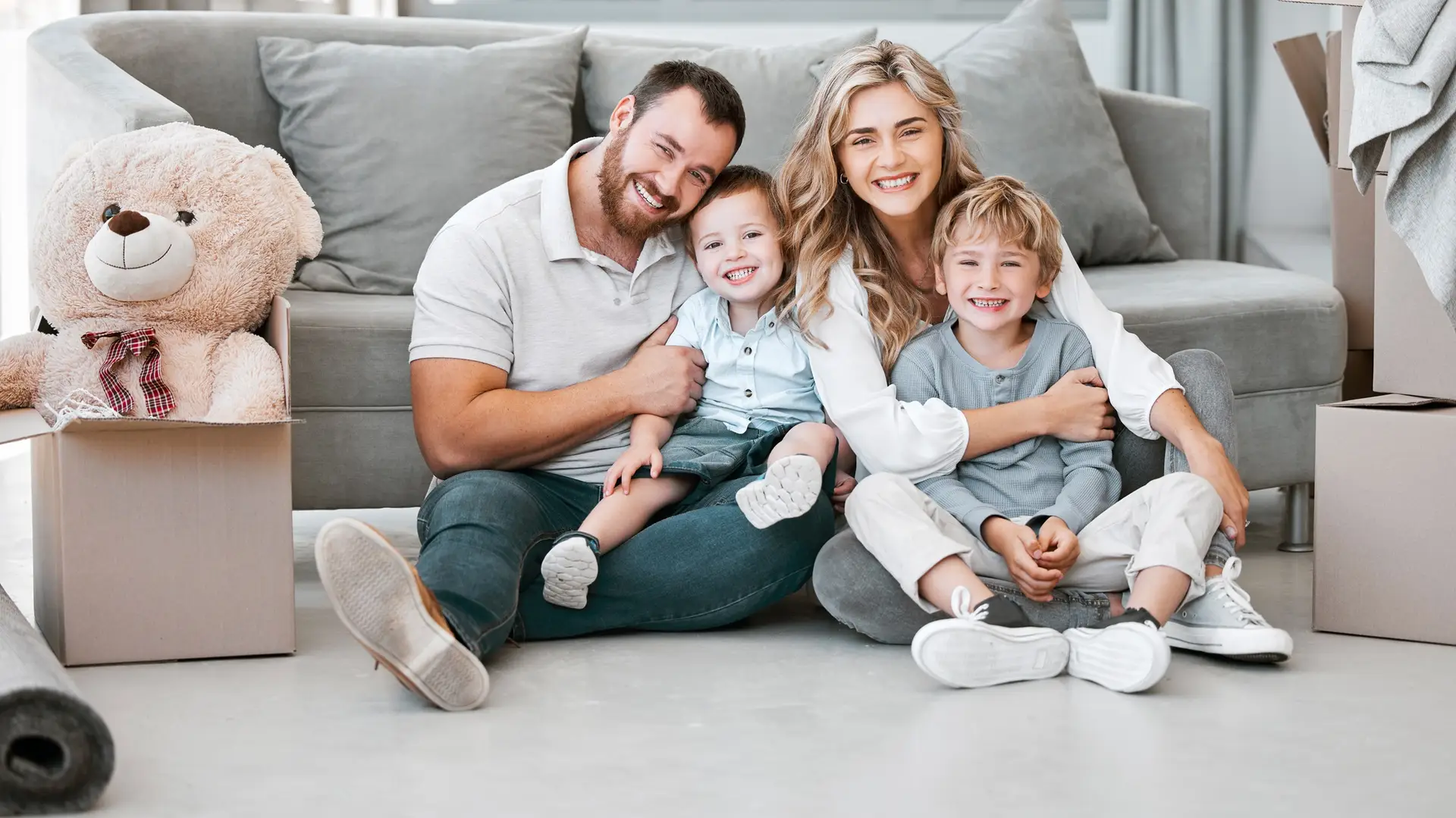 Happy Caucasian Family Sitting Together on Floor - Parents and Children Smiling, Bonding, and Enjoying Quality Time at Home - Representing Family Love and Domestic Harmony