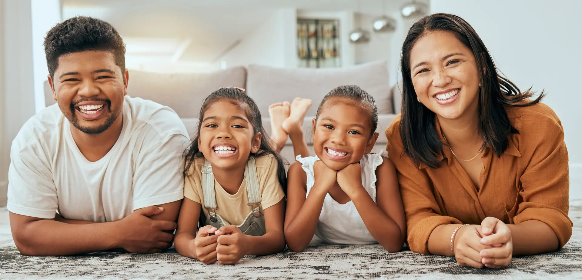 Happy Filipino Family Enjoying Quality Time Together at Home - Smiling Parents and Children Relaxing on Living Room Carpet, Representing Family Protection, Love, and Financial Security