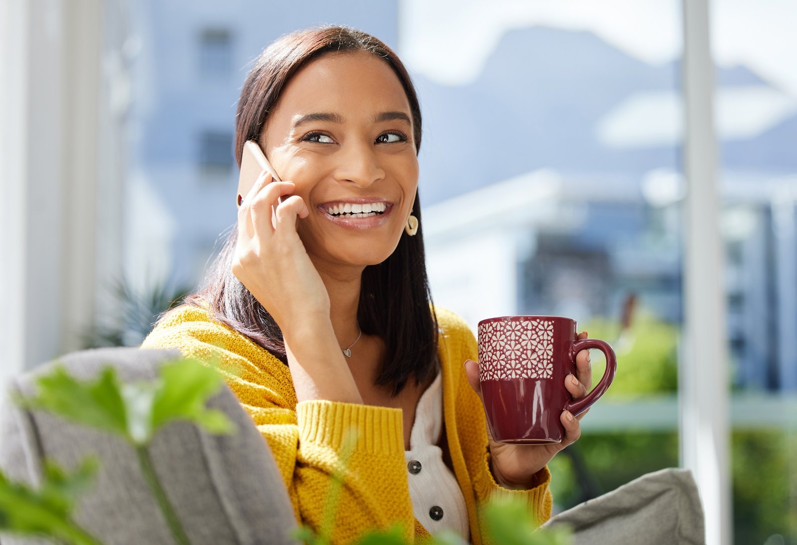 Smiling Dominican woman enjoying coffee while getting a homeowners insurance quote by phone.