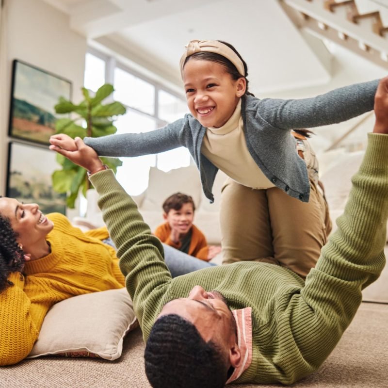 Happy family playing on their living room floor, secured with renters insurance.