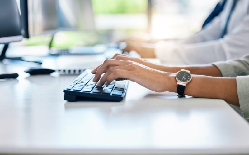 Hands, keyboard and typing with a business woman working on a computer at her desk in the office. F.