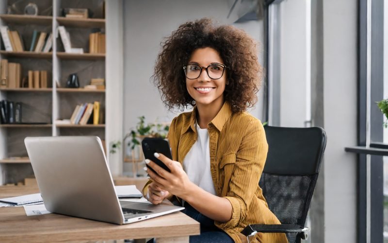 Confident businesswoman multitasking with a laptop and phone in her insured rental space.