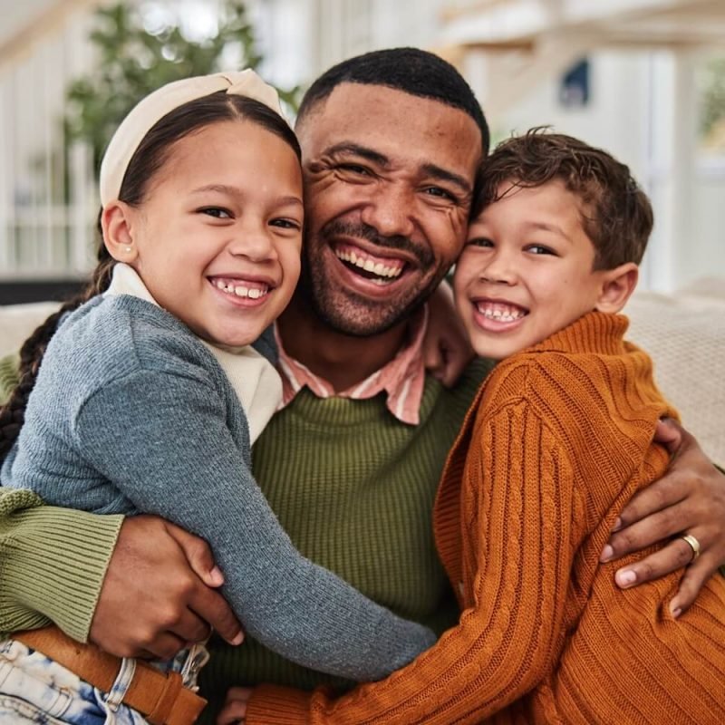 portrait-dad-and-kids-with-hug-on-sofa-for-gratit-2024-07-16-17-11-21-utc